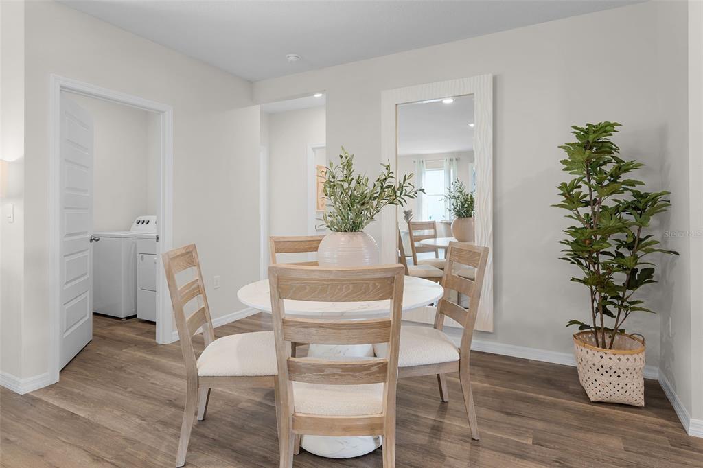 A dining area features a round table with four chairs, a large floor mirror, and a plant — 3954 LIMEKLIN FALLS LOOP, DAVENPORT, FL