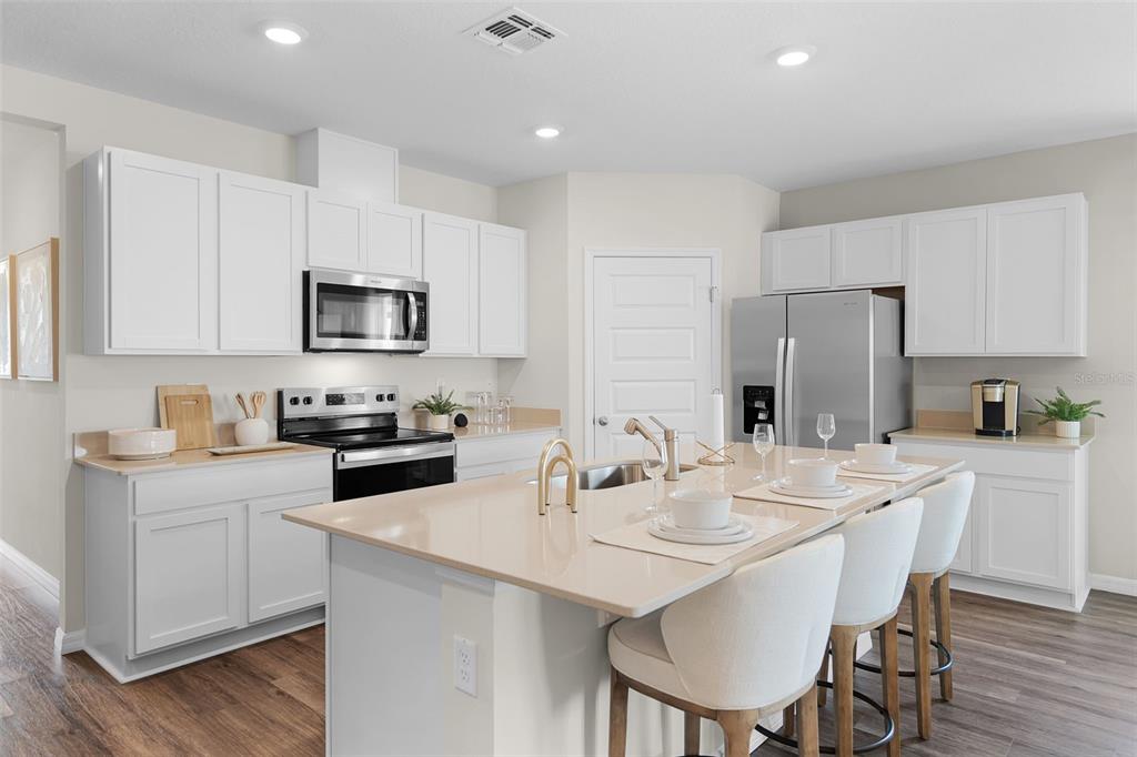A modern kitchen features white cabinets, stainless steel appliances, and a large central island — 3954 LIMEKLIN FALLS LOOP, DAVENPORT, FL
