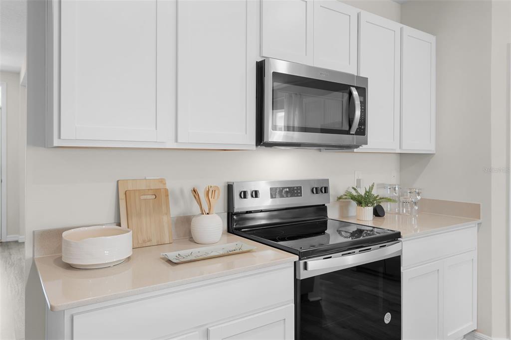 A kitchen features white cabinets, a stainless steel microwave, and a black electric range — 3954 LIMEKLIN FALLS LOOP, DAVENPORT, FL