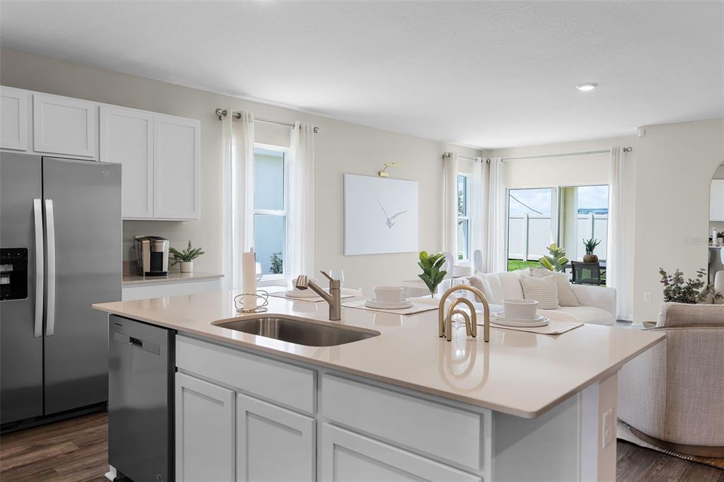 A kitchen island with a stainless steel sink overlooks an open-concept living and dining area — 3954 LIMEKLIN FALLS LOOP, DAVENPORT, FL