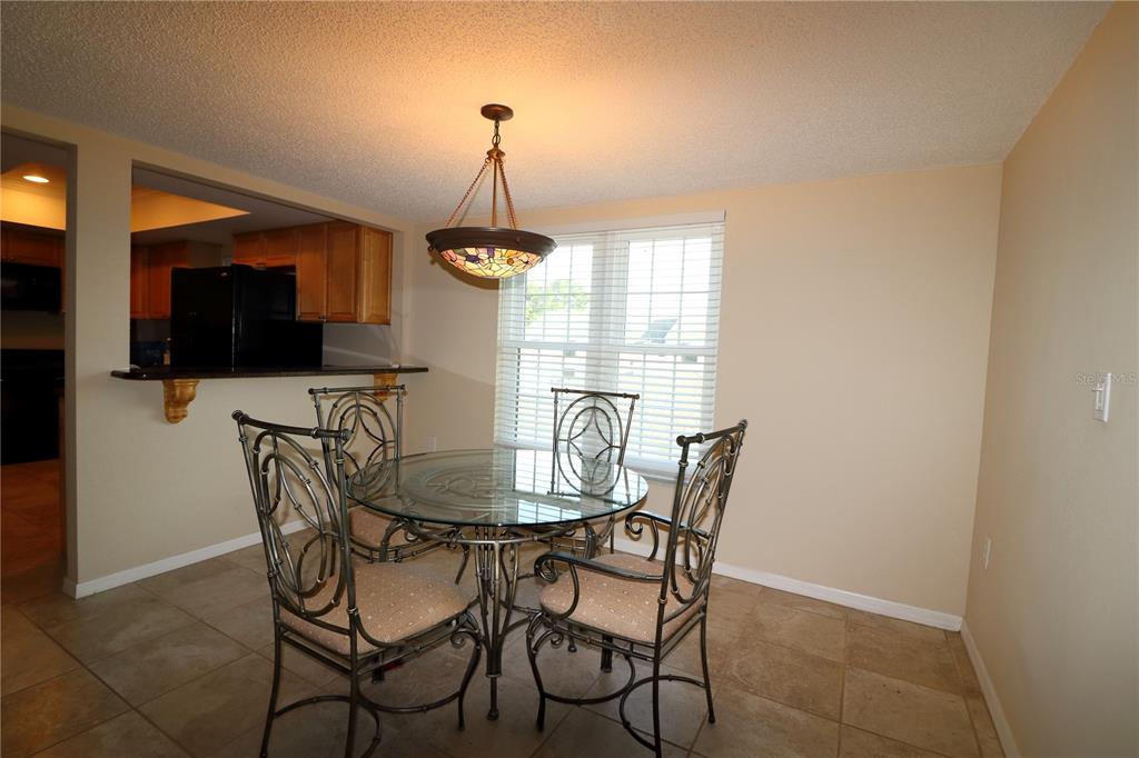 A dining area features a glass-topped table with metal chairs under a stained-glass pendant light — 2465 HERON TERRACE UNIT 202B, CLEARWATER, FL