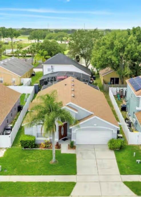 An aerial view of a suburban house with a tan roof, palm tree, and driveway — 522 ROCHESTER LOOP, DAVENPORT, FL