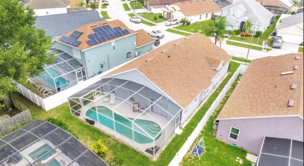 An aerial view shows three suburban houses with screened-in swimming pools and fenced backyards — 522 ROCHESTER LOOP, DAVENPORT, FL