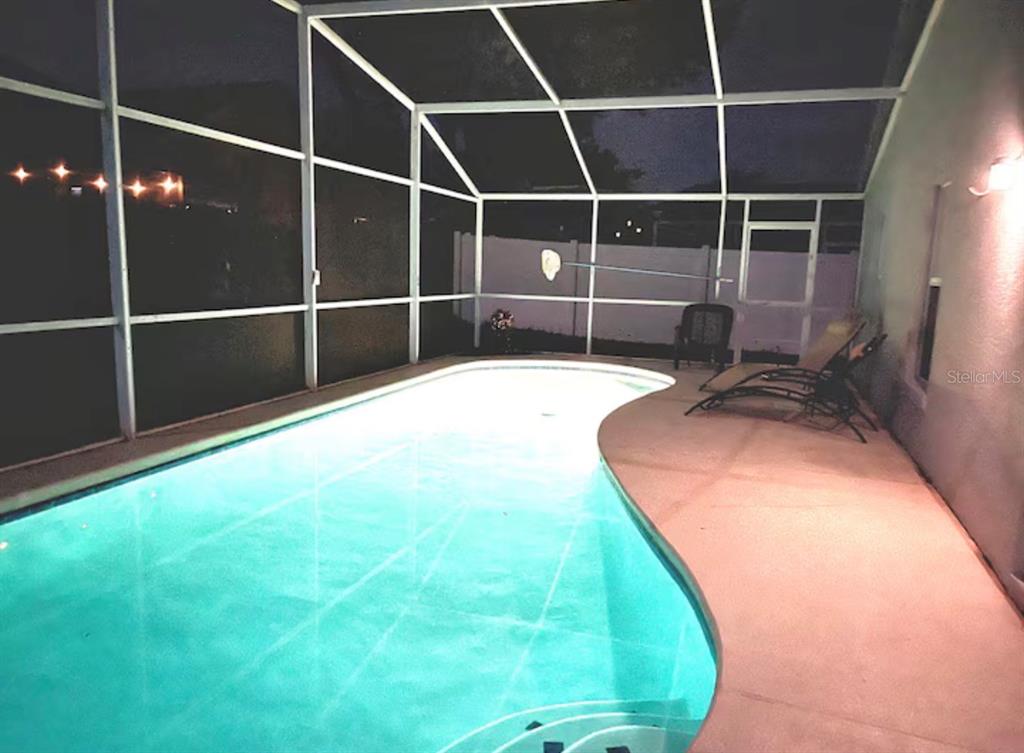 A swimming pool with a screen enclosure and lounge chairs on a concrete patio — 522 ROCHESTER LOOP, DAVENPORT, FL