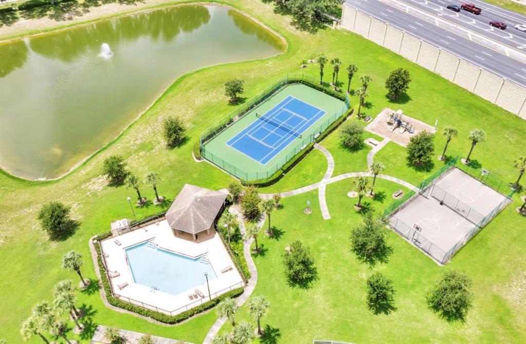 An aerial view shows a community park with a swimming pool, tennis court, and basketball court — 522 ROCHESTER LOOP, DAVENPORT, FL
