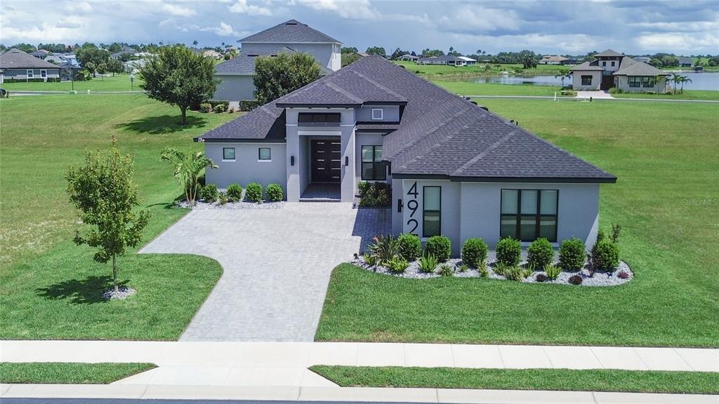 An aerial view of a modern single-story house with a paved driveway and gray exterior — 492 ADAMS VIEW LANE, AUBURNDALE, FL