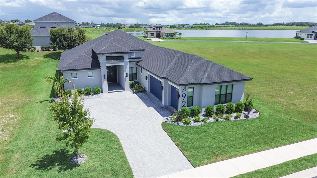 An aerial view of a modern single-story house with a paved driveway and gray exterior — 492 ADAMS VIEW LANE, AUBURNDALE, FL