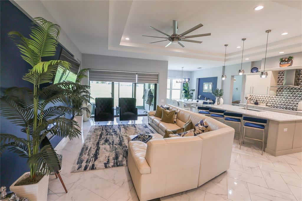 A modern open-concept living room and kitchen featuring white tile floors and blue accents — 492 ADAMS VIEW LANE, AUBURNDALE, FL