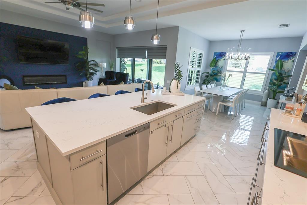 A modern kitchen features a large white quartz island, stainless steel appliances, and marble-look flooring — 492 ADAMS VIEW LANE, AUBURNDALE, FL