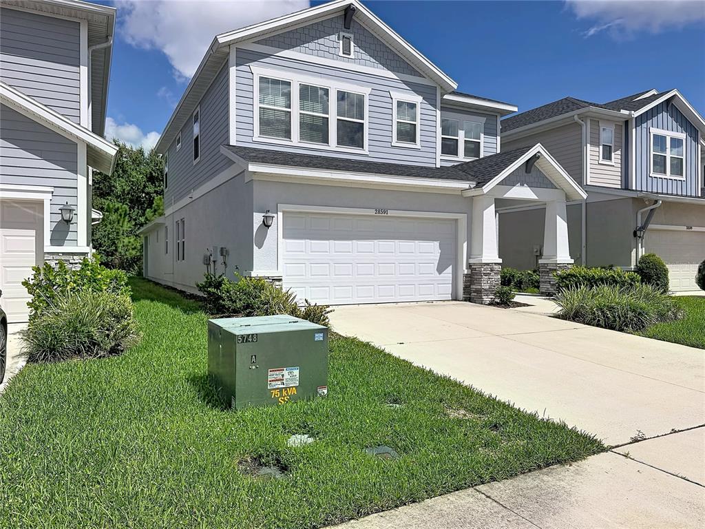 A two-story house with light blue siding and a green utility transformer on the lawn — 28591 COZY CREEK DRIVE, WESLEY CHAPEL, FL