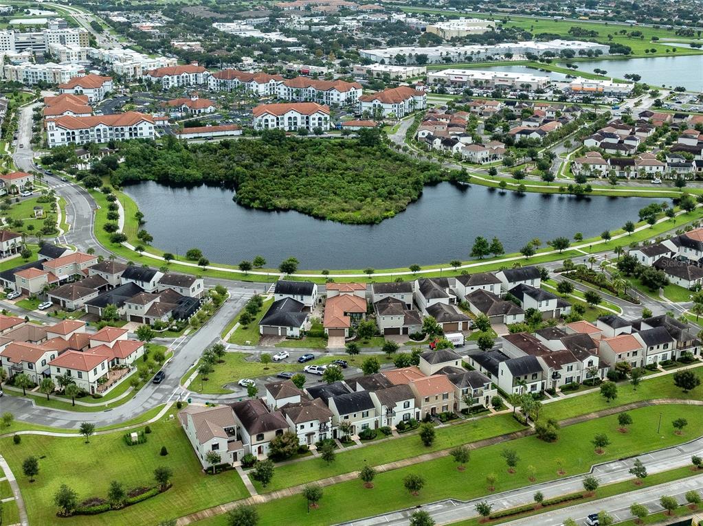 An aerial view of a suburban neighborhood featuring residential homes surrounding a central lake — 8870 NAPOLO DRIVE, MELBOURNE, FL