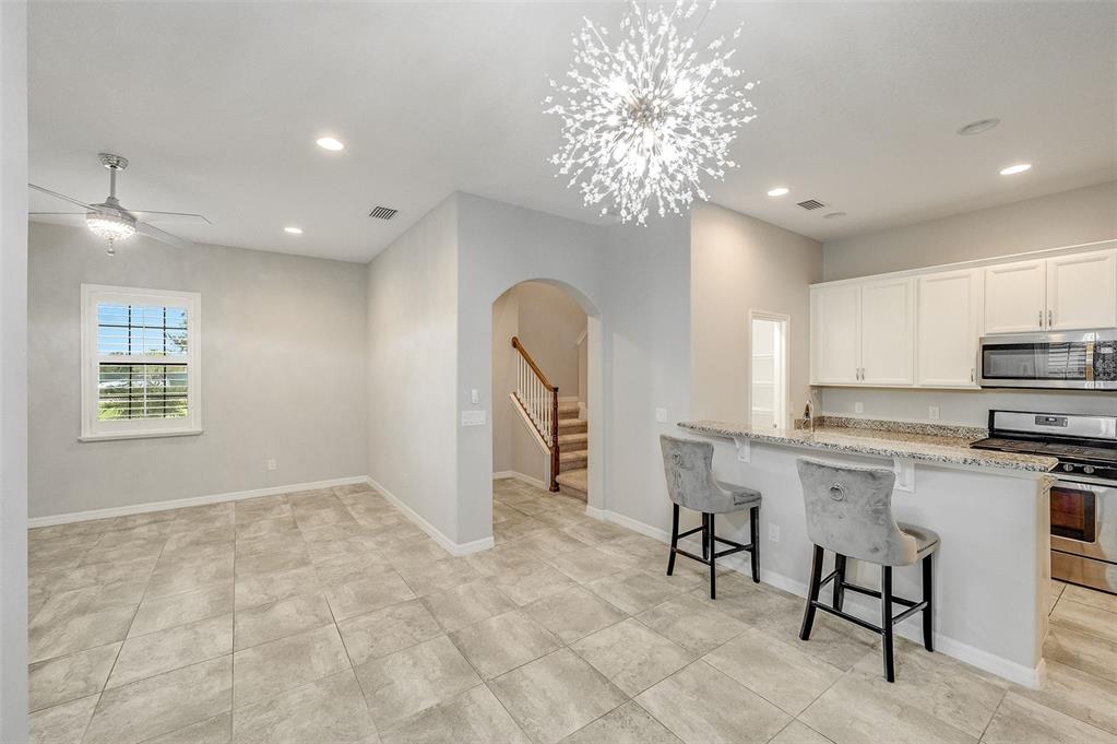 A dining area with tile floors and a chandelier opens to a kitchen with bar seating — 8870 NAPOLO DRIVE, MELBOURNE, FL