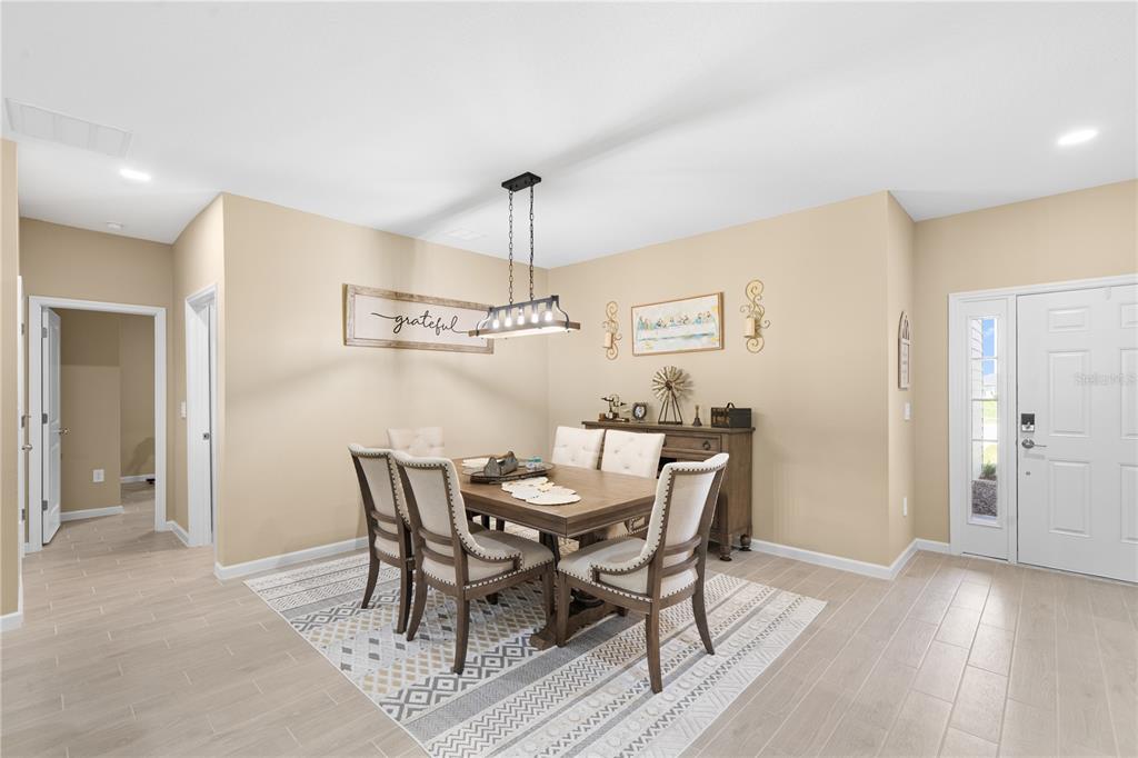 A dining room features a wooden table, upholstered chairs, a pendant light, and tile flooring — 13669 NW CONVERGENCE BOULEVARD, ALACHUA, FL
