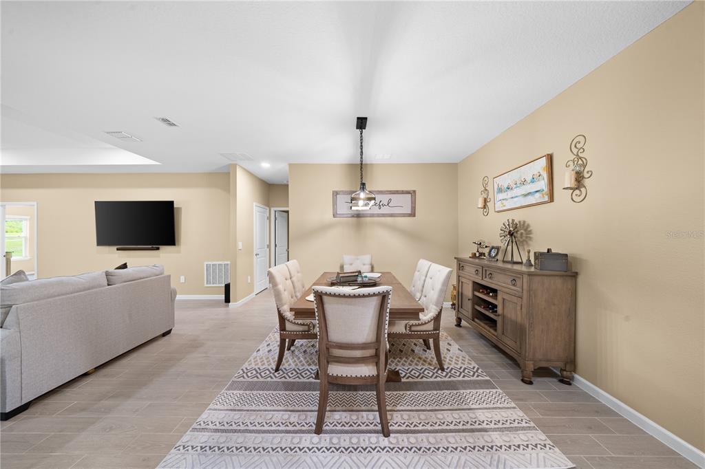A dining room features a wooden table, upholstered chairs, a sideboard, and a patterned rug — 13669 NW CONVERGENCE BOULEVARD, ALACHUA, FL