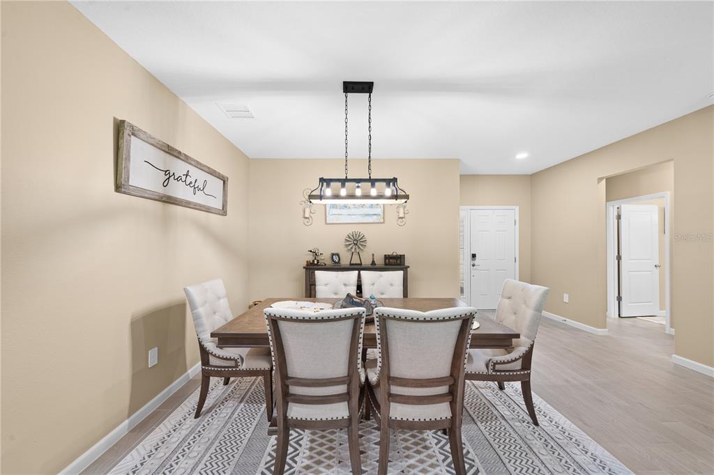 A dining room features a wooden table, upholstered chairs, a chandelier, and a rug — 13669 NW CONVERGENCE BOULEVARD, ALACHUA, FL