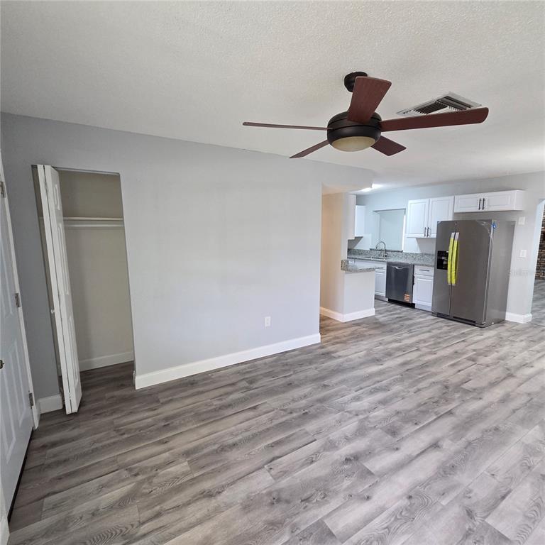 An open living area features light wood-look flooring, a ceiling light fixture, and a red door — 810 SWISS LANE, ORLANDO, FL