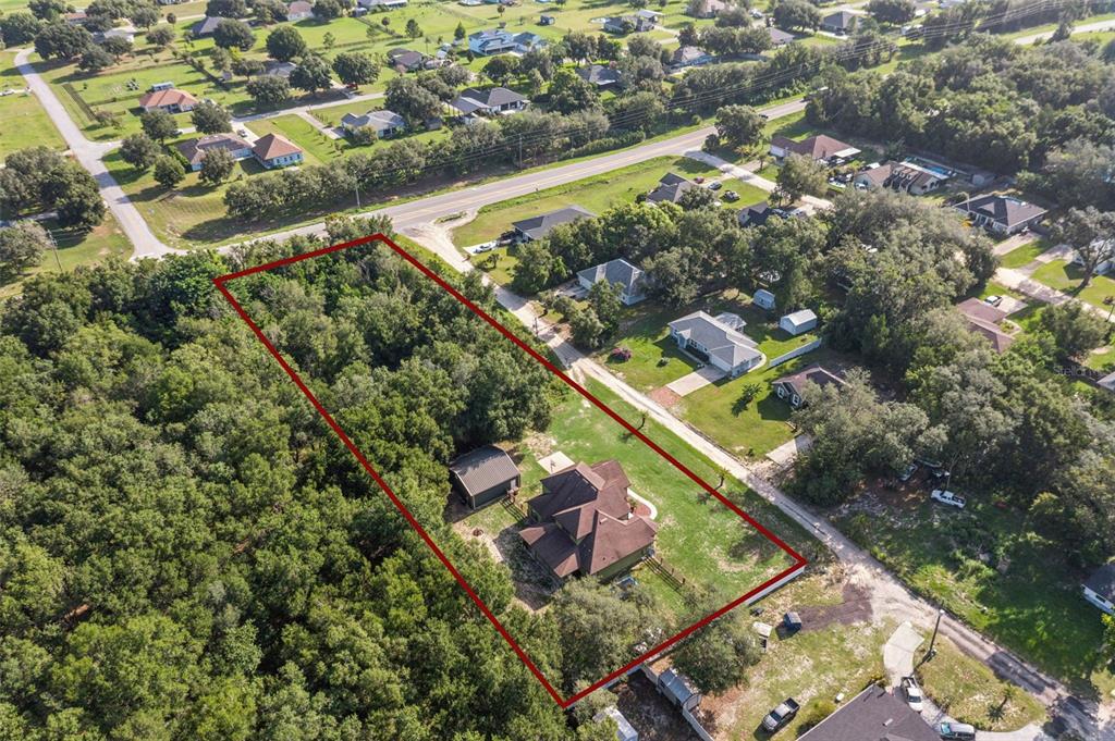 An aerial view shows a house and a detached shed on a large, wooded lot — 36137 MATTAWAN DRIVE, EUSTIS, FL