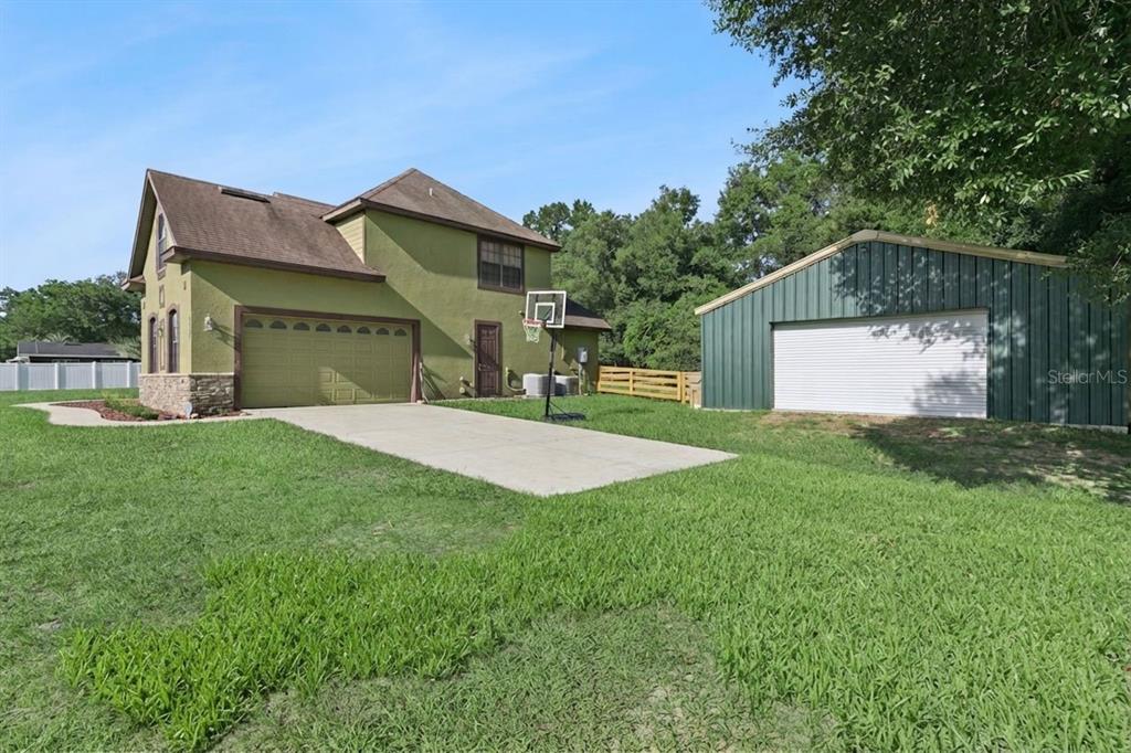 A two-story green house with an attached garage and a separate metal workshop building — 36137 MATTAWAN DRIVE, EUSTIS, FL