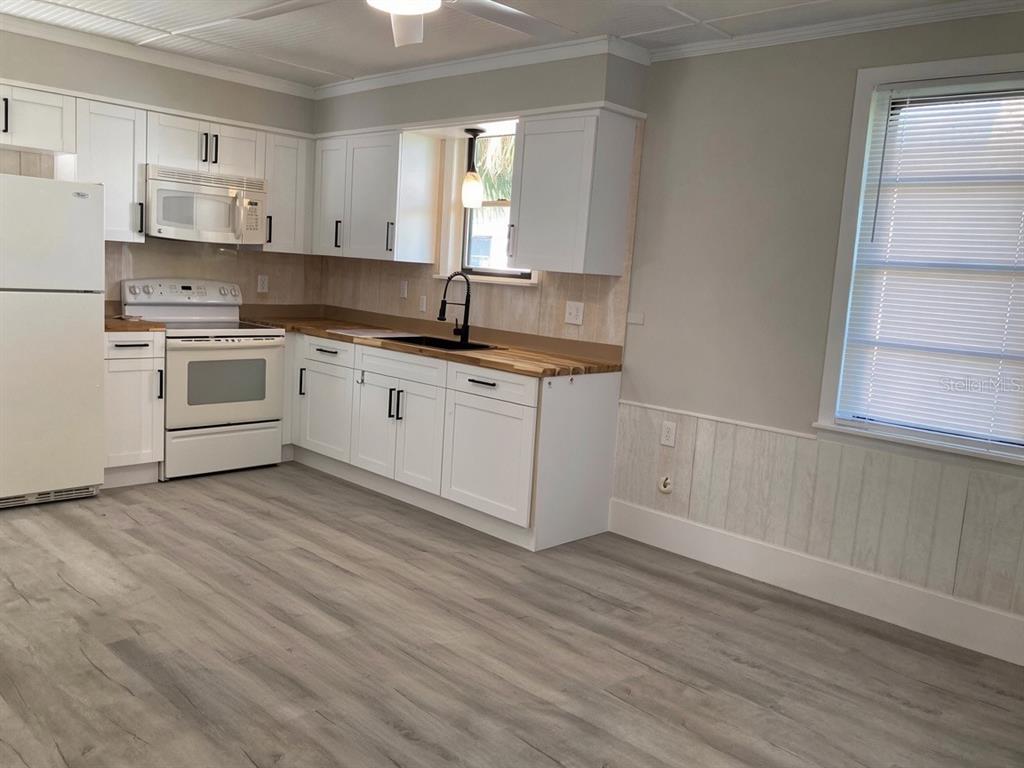 A kitchen with white cabinets, butcher block countertops, a white stove, and a glass table — 31 W OAKWOOD STREET UNIT 2, TARPON SPRINGS, FL