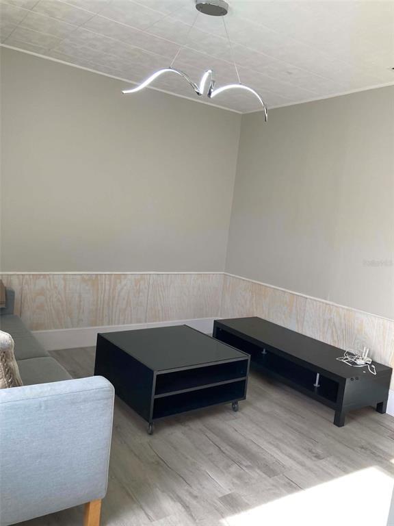 A living room features a grey sofa, light wood-look flooring, and a closet with white doors — 31 W OAKWOOD STREET UNIT 2, TARPON SPRINGS, FL