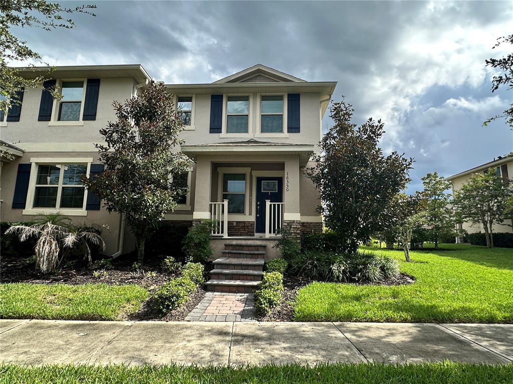 A two-story suburban house with a brick walkway, front porch, and dark blue shutters — 16350 TURNING TIDE WAY, WINTER GARDEN, FL