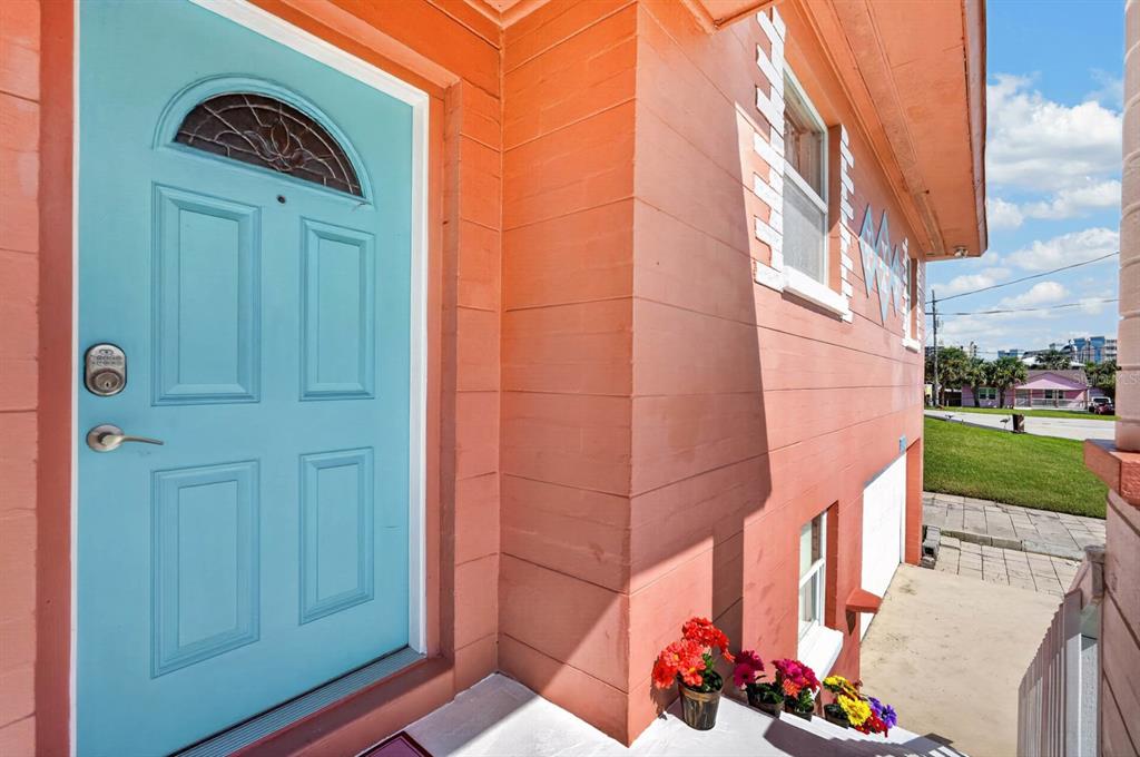 A bright blue front door sits on the side of a peach-colored house — 1910 MARILYN STREET, DAYTONA BEACH, FL
