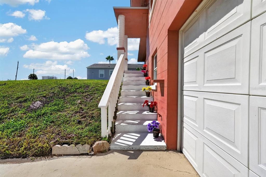 A set of white concrete stairs with potted flowers leads to a raised house entrance — 1910 MARILYN STREET, DAYTONA BEACH, FL