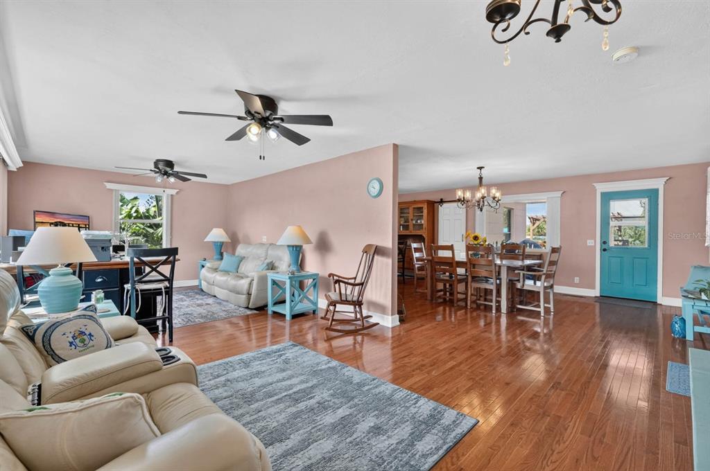A living room and dining area with hardwood floors, light pink walls, and ceiling fans — 1910 MARILYN STREET, DAYTONA BEACH, FL