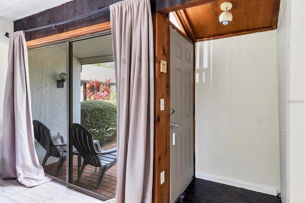 A view from an interior room looking out through a sliding glass door to a patio — 3523 LONGMEADOW UNIT 12, SARASOTA, FL