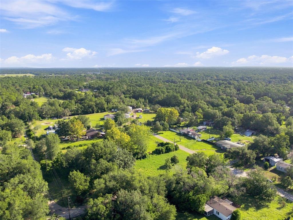 An aerial view shows a rural residential area with scattered houses, trees, and open fields — 18019 GOOD HOPE LANE, SPRING HILL, FL