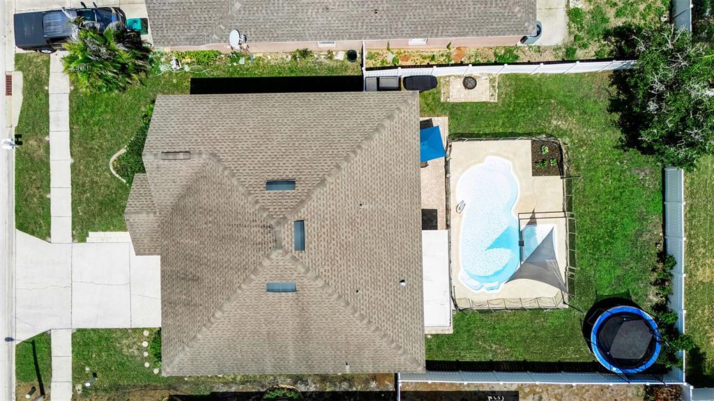 An aerial view shows a house with a shingled roof, a pool, and a trampoline — 1250 LORETTO CIRCLE, ODESSA, FL