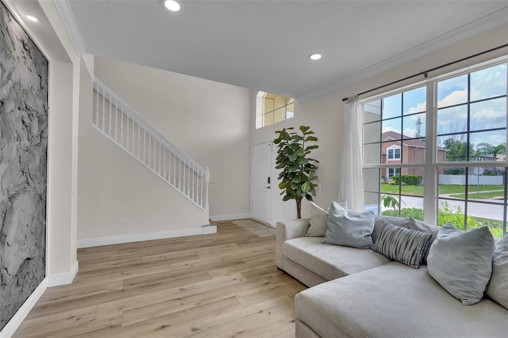 A living room with light wood floors, a staircase, a stone accent wall, and a sofa — 1250 LORETTO CIRCLE, ODESSA, FL