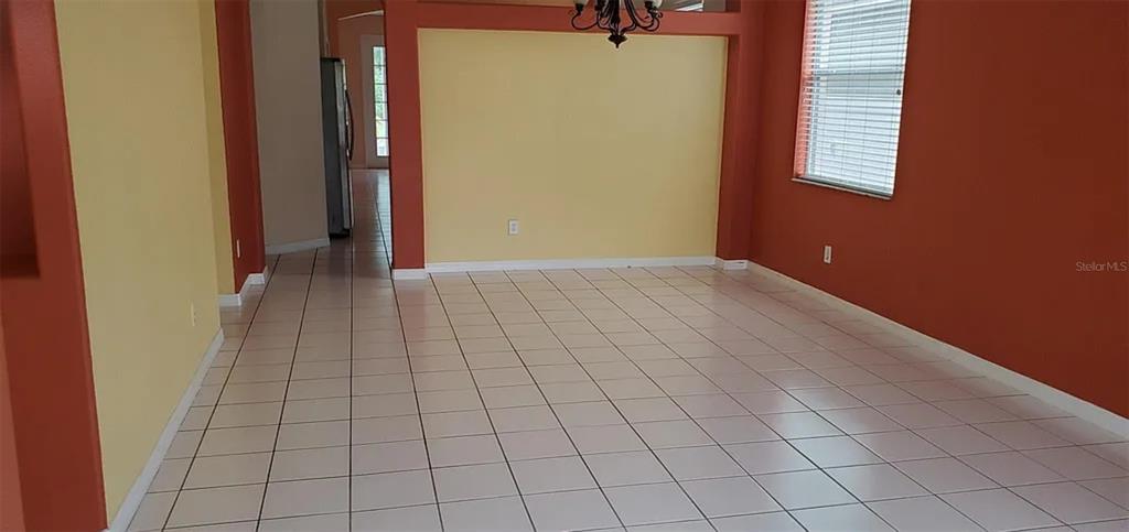 An empty room with light-colored floor tiles, yellow walls, and orange accent walls — 4629 RIVERTON DRIVE, ORLANDO, FL