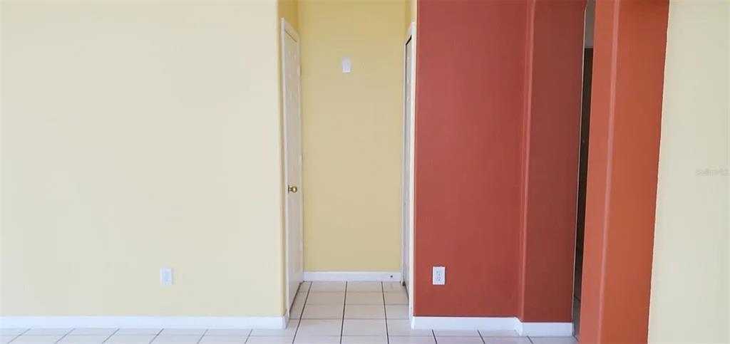 An interior view shows a yellow wall, a red accent wall, and tiled flooring — 4629 RIVERTON DRIVE, ORLANDO, FL