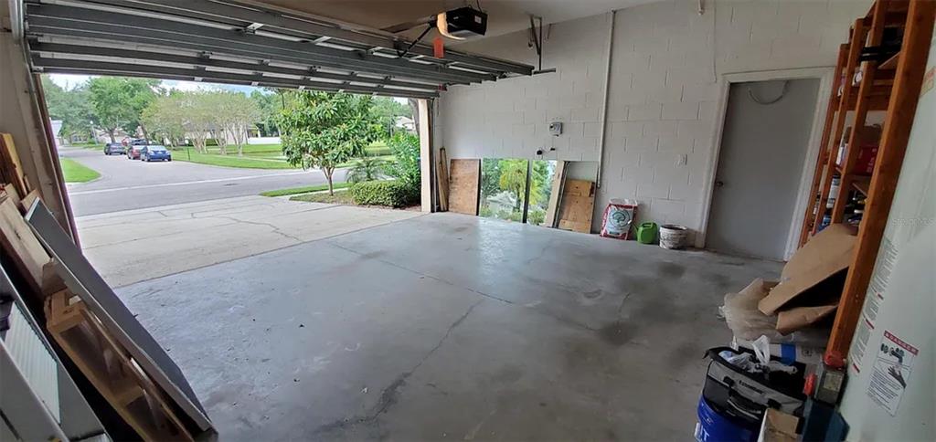 An open garage features a concrete floor, white block walls, and a view of the street — 4629 RIVERTON DRIVE, ORLANDO, FL