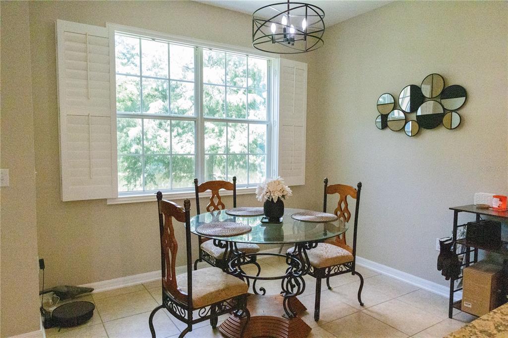 A dining area features a glass-topped table, four chairs, a window with shutters, and wall decor — 2675 RIVER LANDING DRIVE, SANFORD, FL