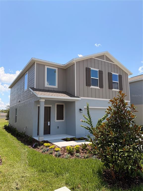 A two-story house with gray vertical siding and a front-facing garage under a blue sky — 2470 HALLOW GARDEN RD, EUSTIS, FL
