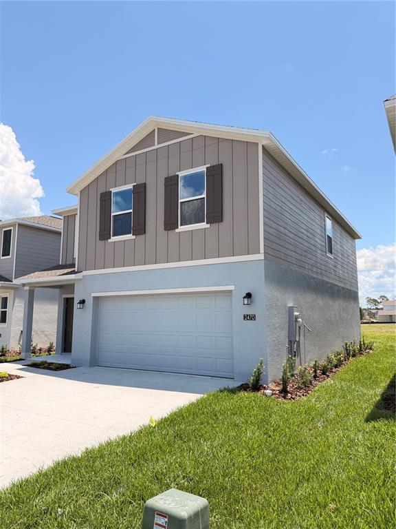 A two-story house features a light blue stucco lower level and tan vertical siding above — 2470 HALLOW GARDEN RD, EUSTIS, FL