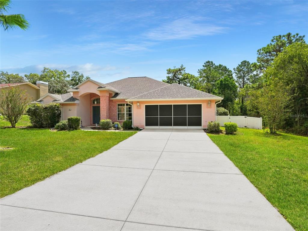 A single-story house with a pink facade, a two-car garage, and a concrete driveway — 56 OAK VILLAGE BOULEVARD, HOMOSASSA, FL