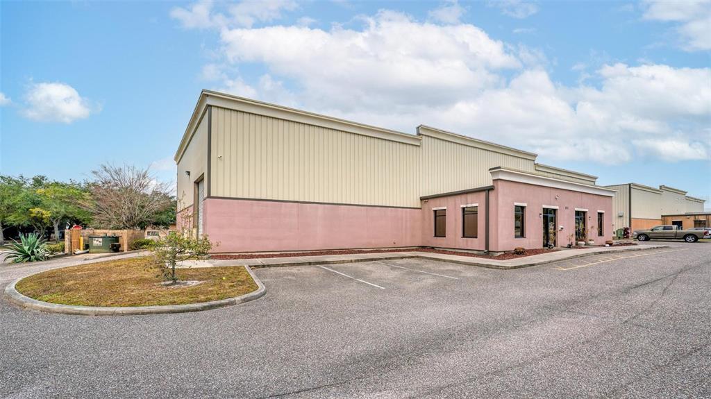 A commercial building with tan metal siding and a pink stucco facade features parking spaces — 551 S ECON CIRCLE, OVIEDO, FL
