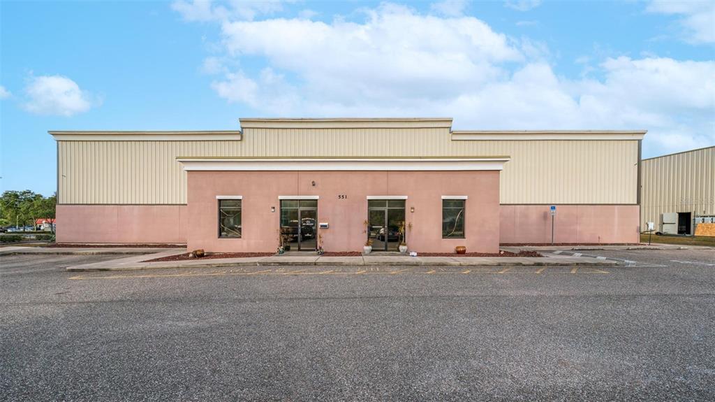 A single-story commercial building with a pink stucco facade and a metal warehouse section — 551 S ECON CIRCLE, OVIEDO, FL
