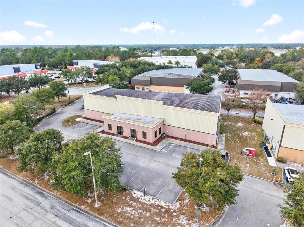 An aerial view shows a commercial building with a parking lot and surrounding trees — 551 S ECON CIRCLE, OVIEDO, FL