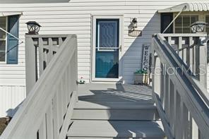 A bright entryway features a white front door with a decorative glass insert and wood-look flooring — 12441 HEXAM ROAD, WEEKI WACHEE, FL