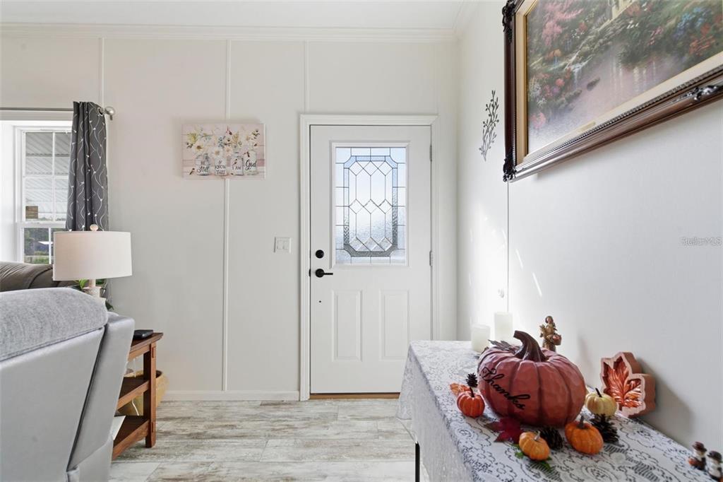 An open-concept living room and kitchen featuring white cabinetry, gray flooring, and a fireplace — 12441 HEXAM ROAD, WEEKI WACHEE, FL