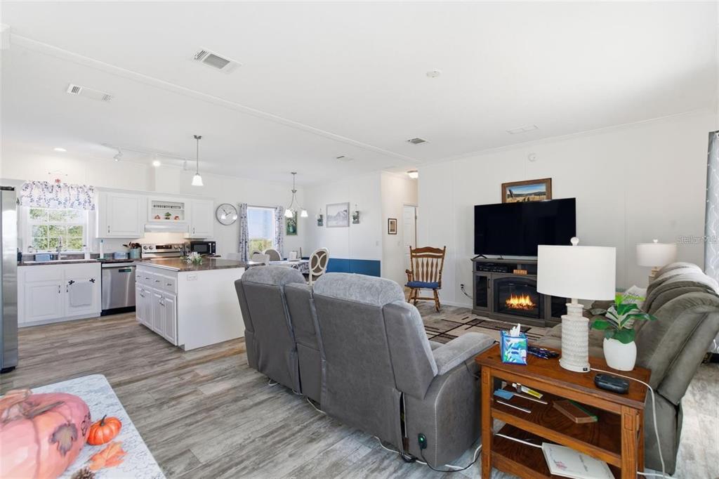 A living room features a gray sofa, a reclining loveseat, a rocking chair, and a fireplace — 12441 HEXAM ROAD, WEEKI WACHEE, FL