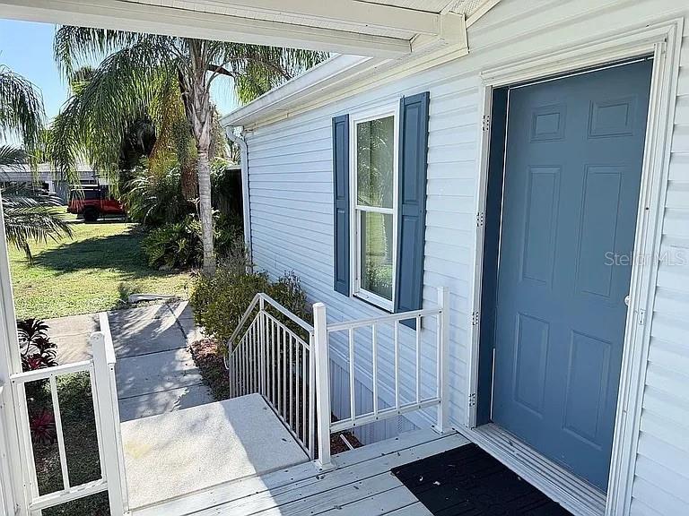A blue front door and white railings lead to a porch on a light-sided house — 2086 STARBOARD DRIVE, GENEVA, FL