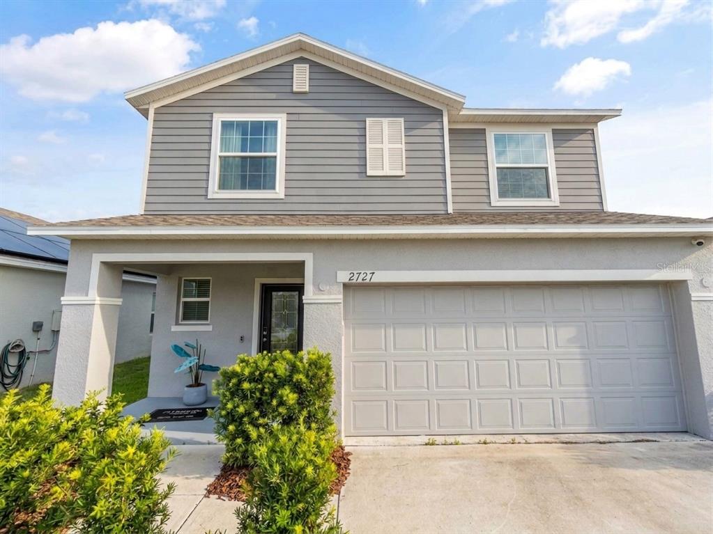A two-story house features gray horizontal siding, a stucco ground floor, and a two-car garage — 2727 SAN MARCO WAY, WINTER HAVEN, FL