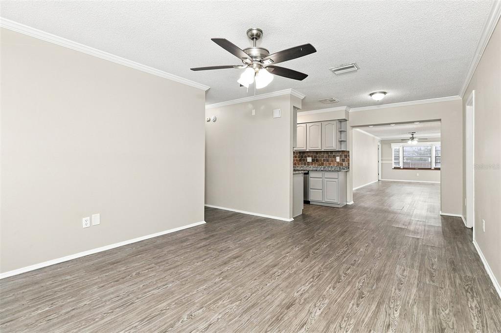 A living room with wood-look flooring, a ceiling fan, a front door, and a window — 8305 AUTUMN OAK AVENUE, PORT RICHEY, FL