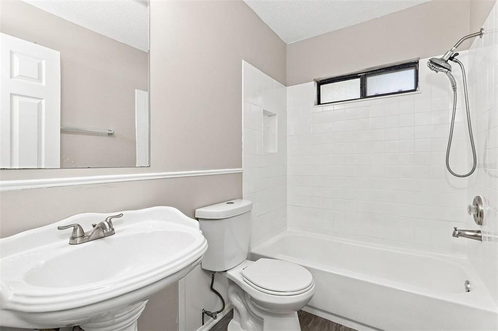 A bedroom with beige carpet, light-colored walls, a window with blinds, and two open closets — 8305 AUTUMN OAK AVENUE, PORT RICHEY, FL