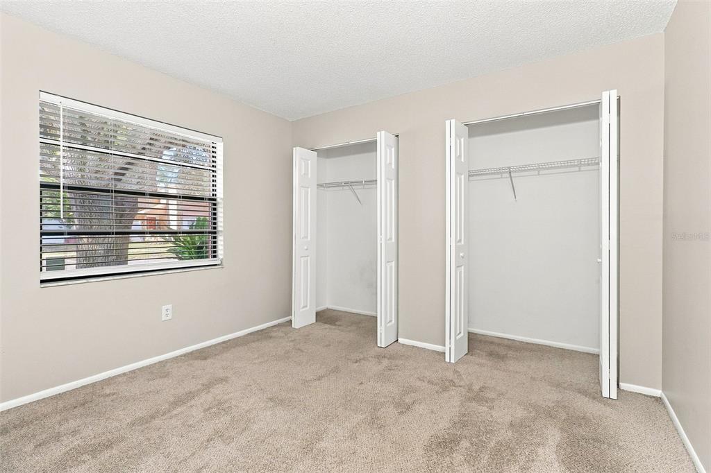 A bedroom with beige walls, tan carpeting, a window with blinds, and a white closet — 8305 AUTUMN OAK AVENUE, PORT RICHEY, FL